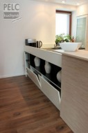 Detail úložného prostoru řešeného pod pracovní deskou s přístupem z jídelny.