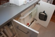 Trubka radiátoru skrytá za dvířky falešné skříňky.