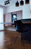 Detail na ostrůvek se stolováním a židlí v pozadí zavěšené segmenty se spotřebiči.