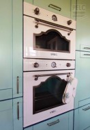Detail na spotřebiče od značky SMEG s rukavicemi, svrchu mikrovlnka a pyrolitická pečící trouba.