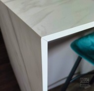 Detail 45° spoje na kompaktní pracovní desce s bílým jádrem.
